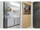 Practical laundry area with washer, dryer, storage shelf, neutral walls, tile flooring and dark painted doors at 1771 Ringling Blvd # 703, Sarasota, FL 34236