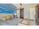Bedroom featuring ocean accent wall, king bed, and sliding closet doors at 211 Cosmopolitan Ct # 211, Sarasota, FL 34236