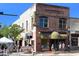 Exterior view of a charming brick building with awnings and outdoor seating on a sunny day at 211 Cosmopolitan Ct # 211, Sarasota, FL 34236