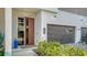 Contemporary home's facade showcases a modern wood door, a stylish garage, and lush landscaping at 211 Cosmopolitan Ct # 211, Sarasota, FL 34236