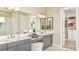 Bright bathroom with double vanity, large mirror, and a large walk-in closet for storage at 26891 Victoria Pl, Punta Gorda, FL 33955
