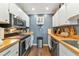 Galley kitchen featuring white cabinets, butcher block countertops, and stainless steel appliances at 303 Grayston Pl # C133, Sun City Center, FL 33573
