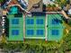 Aerial view of outdoor pickleball courts with green and blue surfaces surrounded by green landscaping and walking paths at 303 Grayston Pl # C133, Sun City Center, FL 33573
