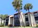 Condo building featuring white stucco, dark accents, a red tile roof, and large palm trees in a landscaped yard at 3231 Beneva Rd # 101, Sarasota, FL 34232