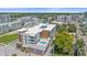 An aerial view showcases a modern condo building with a rooftop pool and lush surroundings at 332 Cocoanut Ave # 406, Sarasota, FL 34236