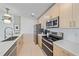 Modern kitchen with stainless steel appliances, light wood cabinets, and white countertop at 332 Cocoanut Ave # 406, Sarasota, FL 34236