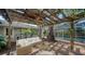 Inviting outdoor seating area under a pergola, featuring comfortable wicker furniture and a view of the screened-in pool at 3716 Camino Real, Sarasota, FL 34239