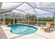 Sparkling pool with screened enclosure, surrounded by lush landscaping and a lake at 406 116Th E St, Bradenton, FL 34212