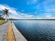 Scenic view of the waterfront with a long paved walkway, grassy area, and boat dock extending into the calm water at 4400 Exeter Dr # J-201, Longboat Key, FL 34228