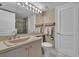 Bright bathroom featuring a single sink vanity, toilet, and a door, complemented by neutral walls and white tiled floor at 6263 Midnight Pass Rd # 105, Sarasota, FL 34242