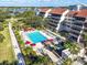 Inviting community pool with a hot tub, lounge chairs, umbrellas, lush landscaping, and condo building at 6263 Midnight Pass Rd # 105, Sarasota, FL 34242