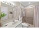 Well-lit bathroom featuring a glass-enclosed shower, neutral tiling, and a decorative plant at 6650 Schooner Bay Cir # 6650, Sarasota, FL 34231