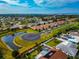 Scenic aerial view of neighborhood with manicured lawns, tranquil pond, and lush greenery at 6907 Costa Bella Dr, Bradenton, FL 34209