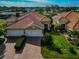 Aerial view of a house with a brick driveway, tile roof, two-car garage, and manicured landscaping at 6907 Costa Bella Dr, Bradenton, FL 34209