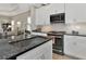 Gourmet kitchen island with sink, sleek appliances, white cabinetry, and granite countertops at 6907 Costa Bella Dr, Bradenton, FL 34209