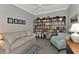 Cozy living room featuring a ceiling fan, light gray walls, a comfy couch, and a bookshelf at 6907 Costa Bella Dr, Bradenton, FL 34209
