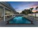 Inviting backyard pool area surrounded by a white fence and lush tropical landscaping at dusk at 7912 Desoto Memorial Hwy, Bradenton, FL 34209