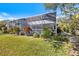 Backyard of home featuring screened-in lanai with tropical plants and landscaped yard at 8579 Woodbriar Dr, Sarasota, FL 34238