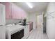 Bright laundry room featuring pink cabinets, modern appliances, tile flooring, and ample counter space at 8579 Woodbriar Dr, Sarasota, FL 34238