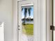 Door and window view of the water and tropical palm trees with green grass under a clear blue sky at 8579 Woodbriar Dr, Sarasota, FL 34238