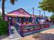 Whimsical Fudge Factory exterior, boasting a pink facade, striped awning, and outdoor seating at 1240 Northport Dr, Sarasota, FL 34242