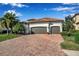 Beautiful home featuring a two-car garage, barrel tile roof and a brick paved drive framed by manicured landscaping at 13303 Swiftwater Way, Lakewood Ranch, FL 34211