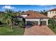 Beautiful home featuring a two-car garage, barrel tile roof and a brick paved drive framed by lush landscaping at 13303 Swiftwater Way, Lakewood Ranch, FL 34211