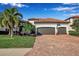 Charming home featuring a two-car garage, barrel tile roof and a brick paved drive framed by lush landscaping at 13303 Swiftwater Way, Lakewood Ranch, FL 34211