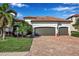 Charming home featuring a two-car garage, barrel tile roof and a brick paved drive framed by lush landscaping at 13303 Swiftwater Way, Lakewood Ranch, FL 34211