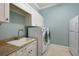 Well-lit laundry room with sink, modern washer and dryer, and ample cabinet space at 16416 Baycross Dr, Lakewood Ranch, FL 34202