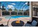 A stunning screened pool area with a fire pit and a view of the tennis court offers the ultimate outdoor experience at 16416 Baycross Dr, Lakewood Ranch, FL 34202