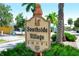 Entrance to Southside Village shops with lush greenery, a decorative sign, and a glimpse of nearby stores at 1735 Flower Dr, Sarasota, FL 34239