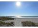 Scenic beach view featuring a sandy path leading to the ocean under a sunny sky at 1932 Harbourside Dr # 244, Longboat Key, FL 34228