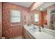 Bathroom featuring patterned wallpaper, vanity, large mirror, and shower at 19484 Midway Blvd, Port Charlotte, FL 33948