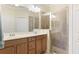 Bathroom with double sinks, wood cabinets, a shower with a glass door, and good lighting at 20170 Benissimo Dr, Venice, FL 34293