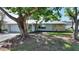 Charming home featuring an attractive stone accent wall, a well-manicured lawn, and mature shade trees at 22151 Lancaster Ave, Port Charlotte, FL 33952