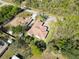 An aerial view of a well-maintained property with a terracotta roof, lush green lawn, and mature trees, surrounded by nature at 23117 Hammond Ave, Port Charlotte, FL 33954