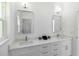 A modern bathroom featuring double sinks, white cabinets and hardware, framed mirrors, and updated light fixtures at 23117 Hammond Ave, Port Charlotte, FL 33954