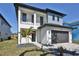 This modern two-story home features a gray garage door and a minimalist front yard with a young palm tree at 2345 Oak Ter, Sarasota, FL 34231