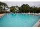 Large community swimming pool surrounded by lounge chairs and lush green trees at 2755 Coconut Bay Ln 1K # 119, Sarasota, FL 34237