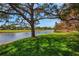 Picturesque backyard view of the lake with lush green grass and mature trees at 2961 Taywood Mdws # 26, Sarasota, FL 34235