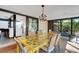 Stylish dining area with a contemporary yellow table and chairs, overlooking a lush backyard with a view of the kitchen at 3026 Mayflower St, Sarasota, FL 34231