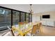 Chic dining room with a unique yellow table, mid-century modern chandelier, and ample natural light from large windows at 3026 Mayflower St, Sarasota, FL 34231