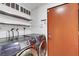 Modern laundry room with stainless steel shelving, Samsung washer and dryer, and a vibrant orange door at 3026 Mayflower St, Sarasota, FL 34231