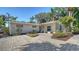 Inviting front entrance featuring a stone-paved courtyard with lush landscaping, seating, and quaint architectural details at 3530 Flores Ave, Sarasota, FL 34239