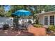 Cozy patio with brick floor, an umbrella table set, a grill, and surrounding plants at 3530 Flores Ave, Sarasota, FL 34239