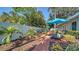 Outdoor patio with brick pavers, lounge chairs, and shade umbrellas surrounded by lush landscaping at 3530 Flores Ave, Sarasota, FL 34239