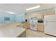 Well-lit kitchen featuring white appliances, light wood cabinets, and a breakfast bar at 4061 Crockers Lake Blvd # 2611, Sarasota, FL 34238