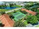 Aerial view of well-maintained tennis courts surrounded by lush greenery and community buildings at 4061 Crockers Lake Blvd # 2611, Sarasota, FL 34238