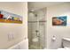 Elegant bathroom with glass shower, pebble floor and beach themed art at 4307 Gulf Dr # 208, Holmes Beach, FL 34217